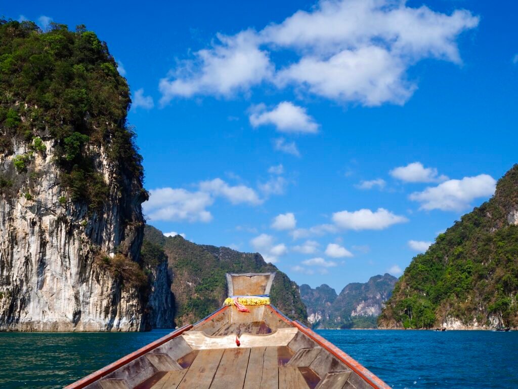 Experience the scenic beauty of Khao Sok Lake with cliffs and vibrant skies.