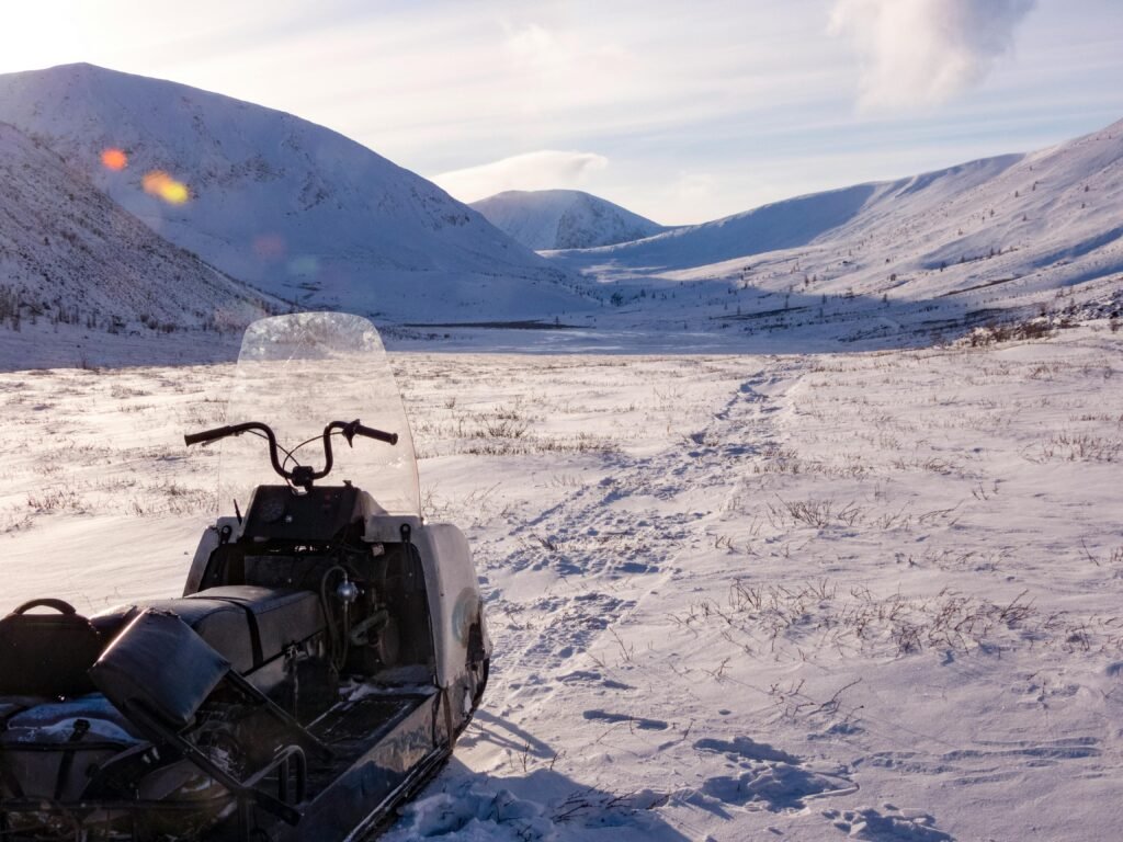 Snowmobile parked on a snowy terrain with mountainous winter backdrop.