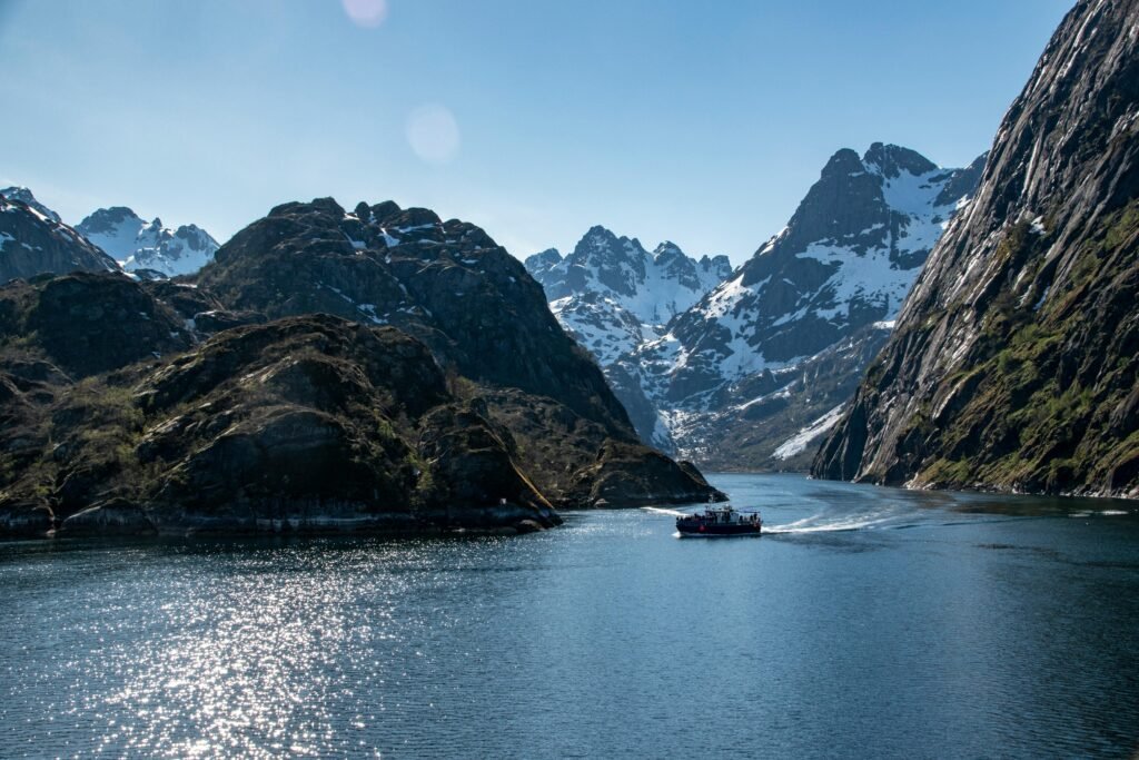 Stunning view of a snowcapped mountain fjord with a tranquil waterway and a boat sailing through.