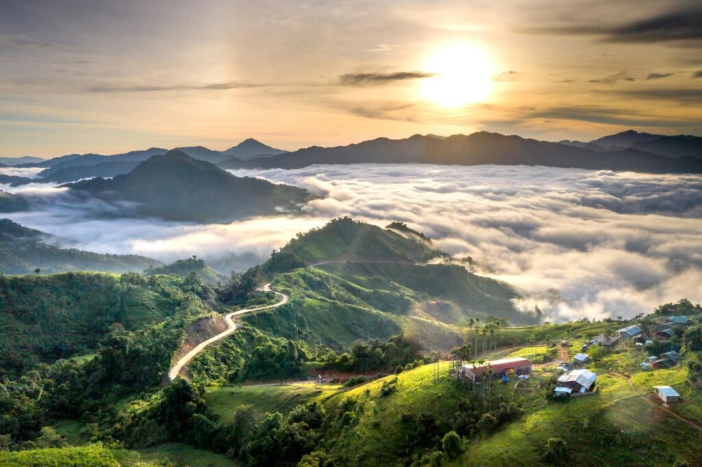 A stunning aerial view of green hills with a sunrise and clouds in the distance.