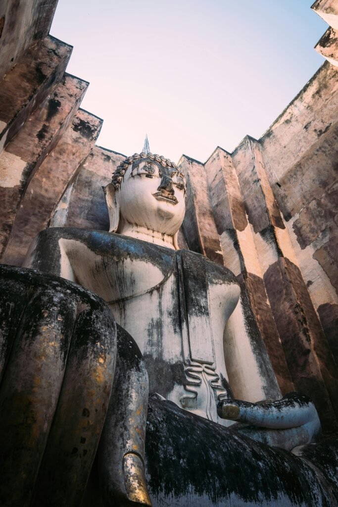 Captivating vertical shot of the Buddha statue in Wat Si Chum, Sukhothai Historical Park, Thailand.