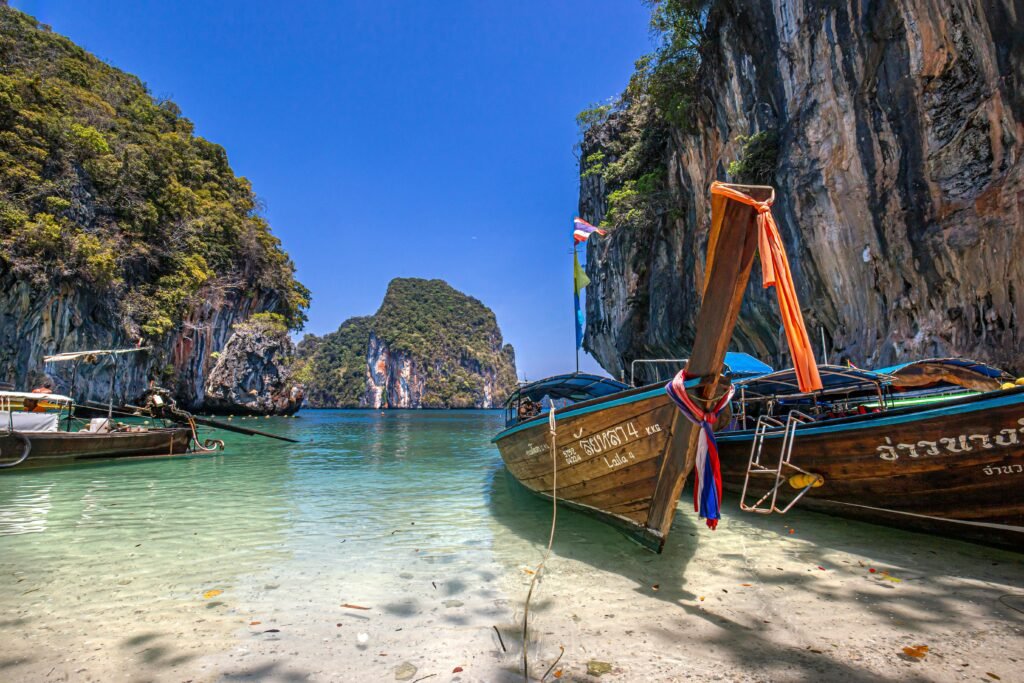 Scenic view of traditional Thai long-tail boats moored in Ao Nang's clear waters, with limestone cliffs in the background.
