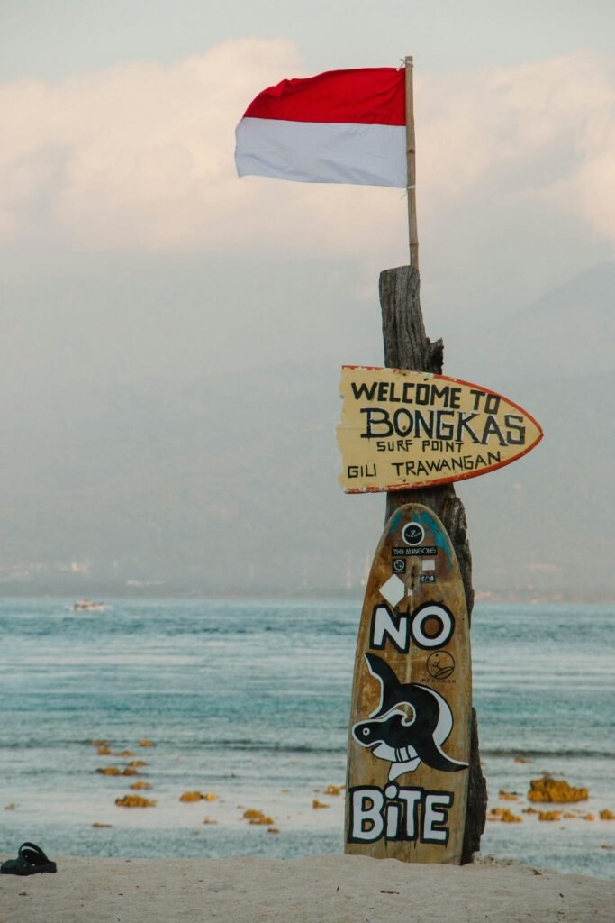 Colorful surf point sign with flag at Gili Trawangan beach, indicating popular surf spot and safety message.