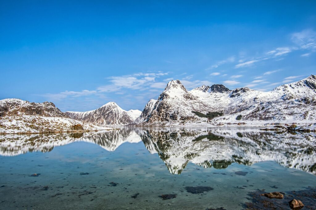 Reflection of snow-capped mountains in a tranquil lake in Lofoten, Norway.