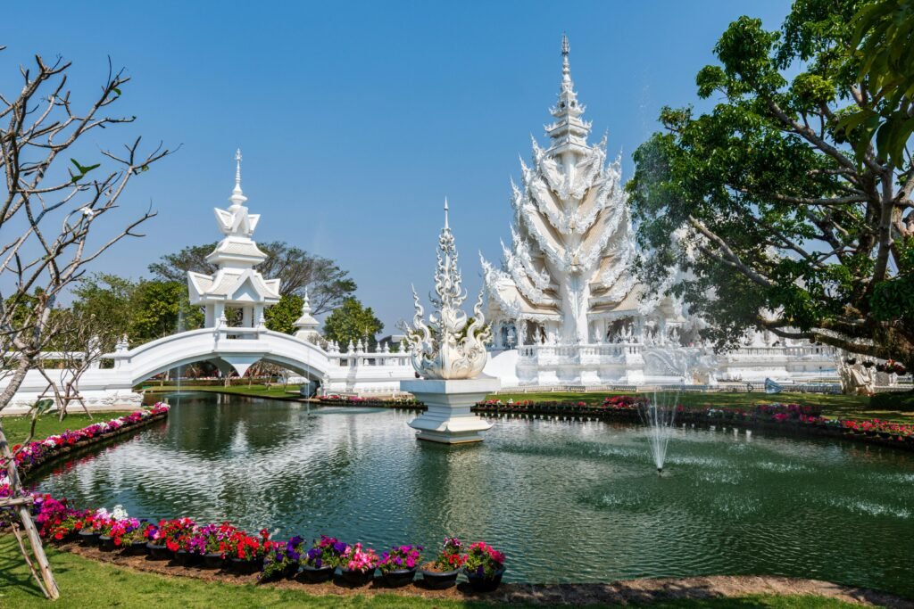 A breathtaking view of the intricate Wat Rong Khun temple in Chiang Rai, Thailand, with vibrant gardens and serene water features.