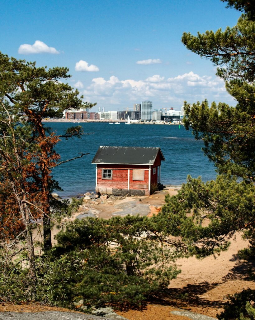 Discover the serene beauty of Helsinki's coast featuring a classic Nordic cabin and city skyline.