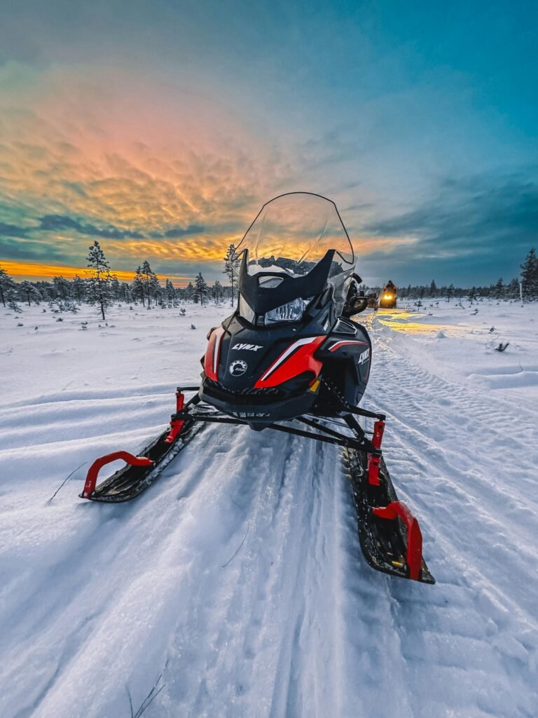 A vibrant snowmobile on snowy terrain during a breathtaking winter sunset, ideal for adventure themes.