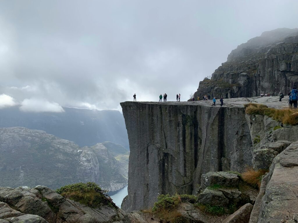 Hikers enjoy a breathtaking view from Preikestolen, a famous cliff in Norway.