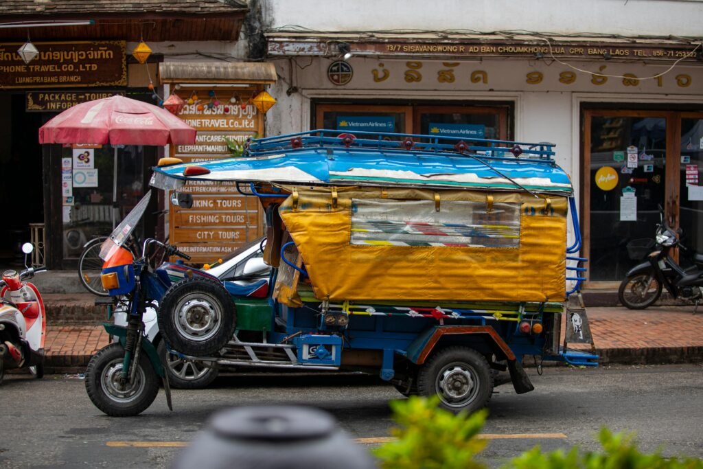 Colorful auto rickshaw parked on a busy street in Luang Prabang, Laos.