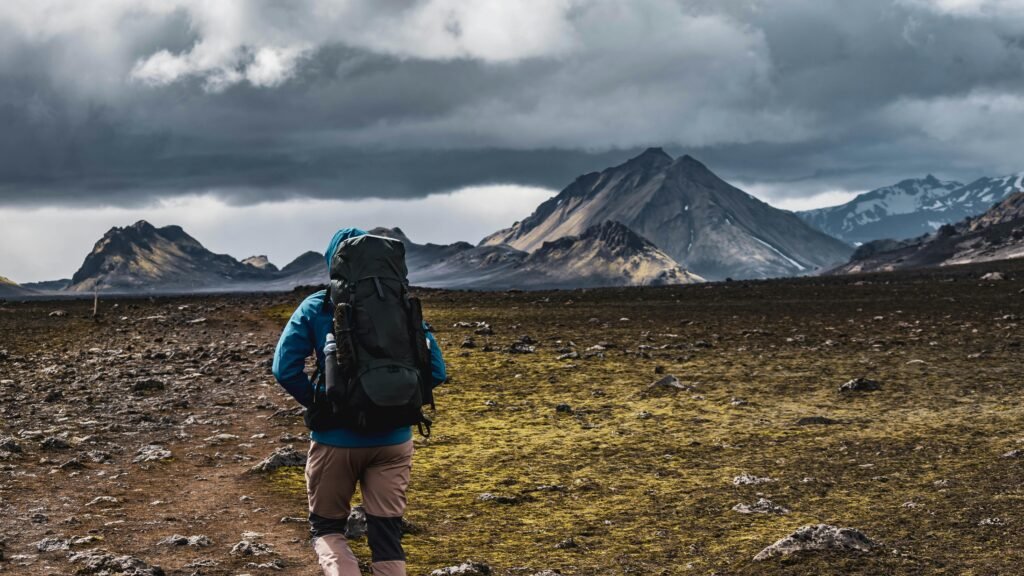 A lone hiker trek across a rugged path with stunning mountain background in Iceland, showcasing adventure.