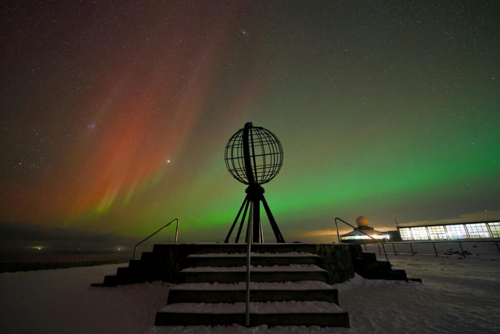 A breathtaking view of the Northern Lights over the North Cape, Norway's iconic globe monument.