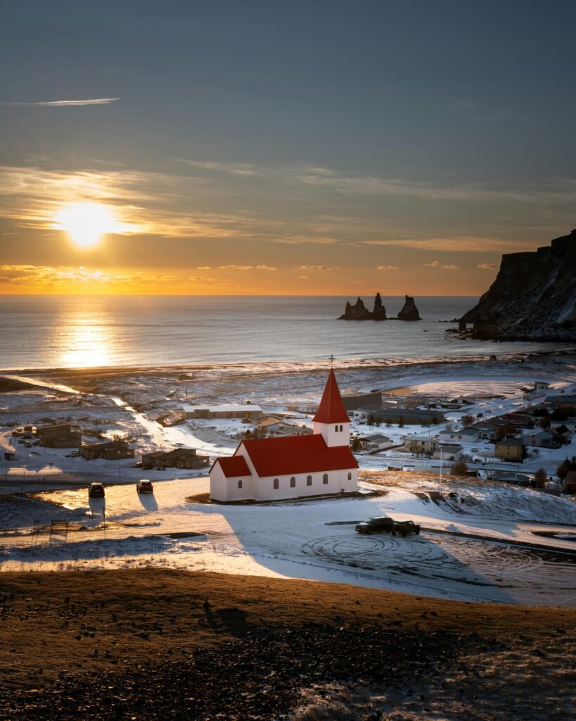 Beautiful sunset over Vík Church in a snowy Icelandic winter landscape.