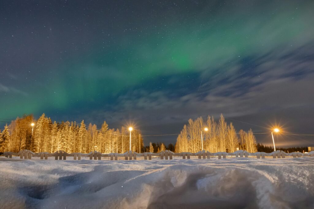 Stunning Northern Lights illuminate a snowy night sky in Lapland, Finland's winter wonderland.