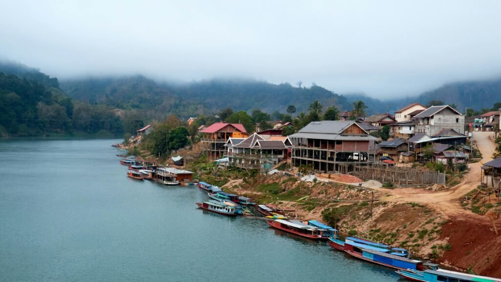 Peaceful morning view of Nong Khiaw, Laos, with misty mountains and a scenic river.