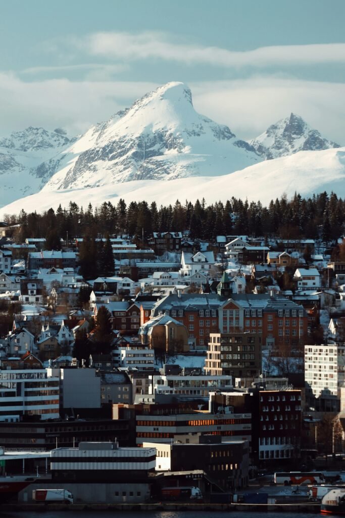 Explore the stunning winter landscape of Tromsø, Norway, with snow-covered mountains and charming architecture.