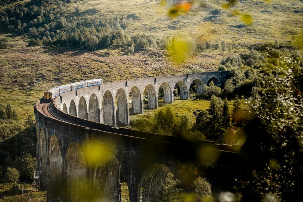A train travels over the iconic Glenfinnan Viaduct in Scotland's picturesque landscape.