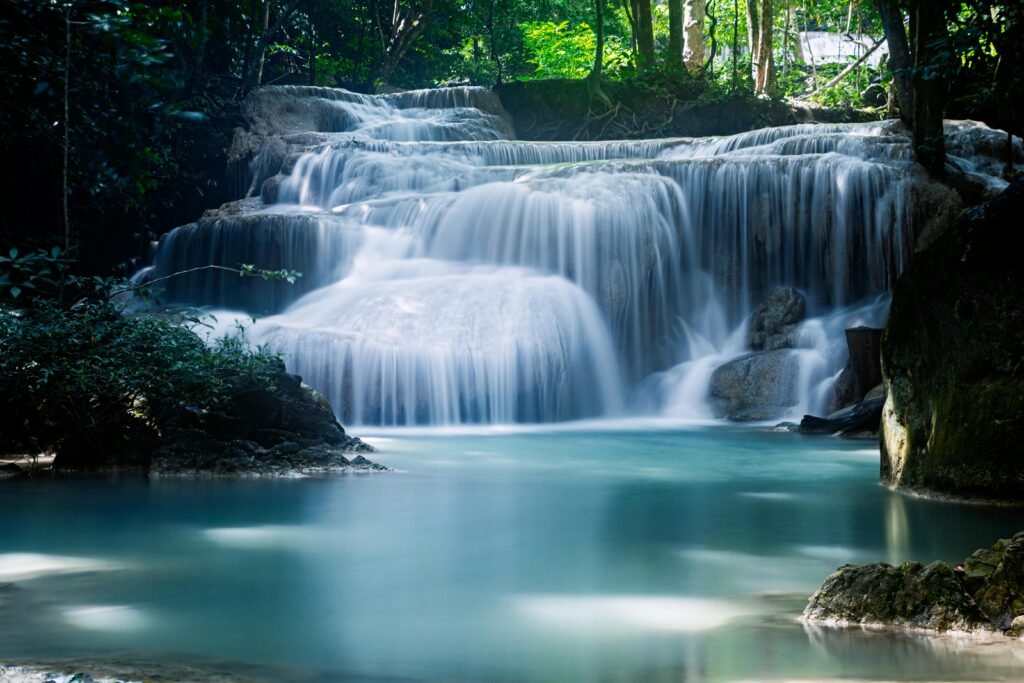 A tranquil waterfall cascading through lush greenery in a tropical forest setting, captured in daylight.