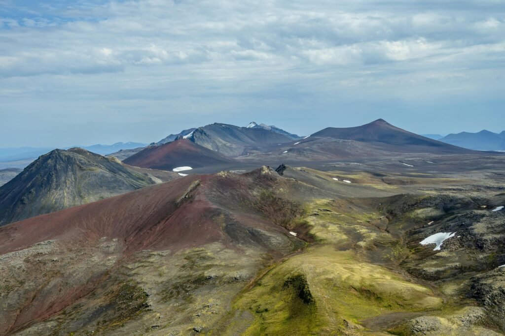 Stunning aerial view of volcanic mountains with colorful peaks and rugged terrain in Iceland.