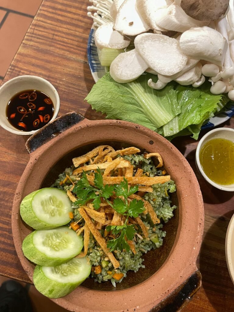 Delicious Vietnamese vegetarian claypot dish with rice, crispy tofu, cucumbers, and fresh greens.
