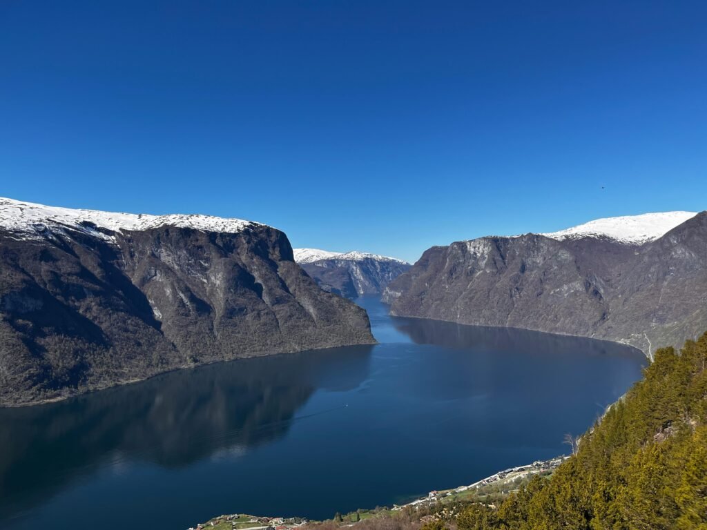 Breathtaking aerial view of the Sognefjord surrounded by snow-capped mountains under a clear blue sky in Norway.