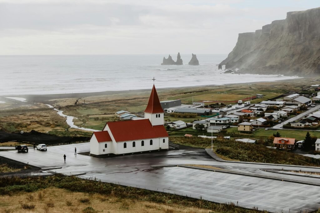 Explore the picturesque Vik i Myrdal Church with cliffs and ocean backdrop in Iceland's coastal town.