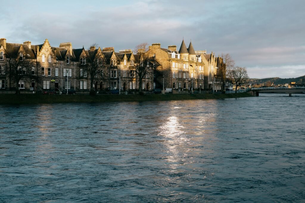Charming Victorian buildings by the river in Inverness, Scotland, reflecting in the water at sunrise.
