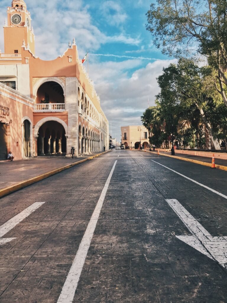 Scenic view of a historical street in Mérida showcasing colonial architecture under a vibrant sky.