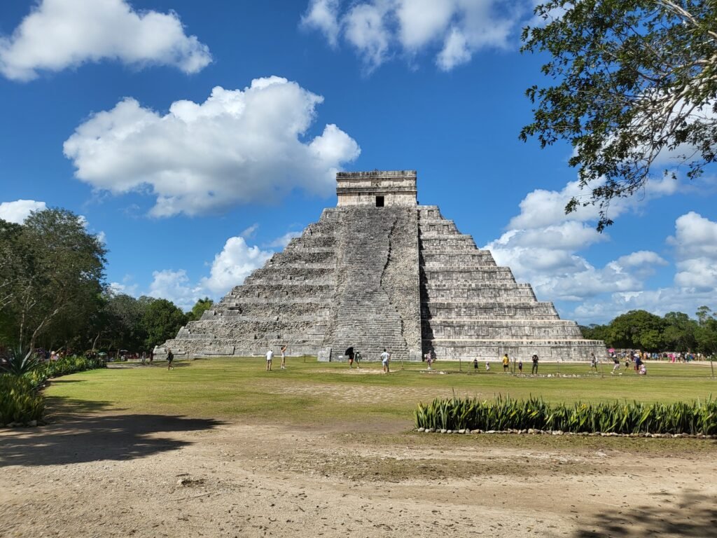 Historic El Castillo pyramid under blue skies in Chichén Itzá, a famous Mayan landmark in Mexico.
