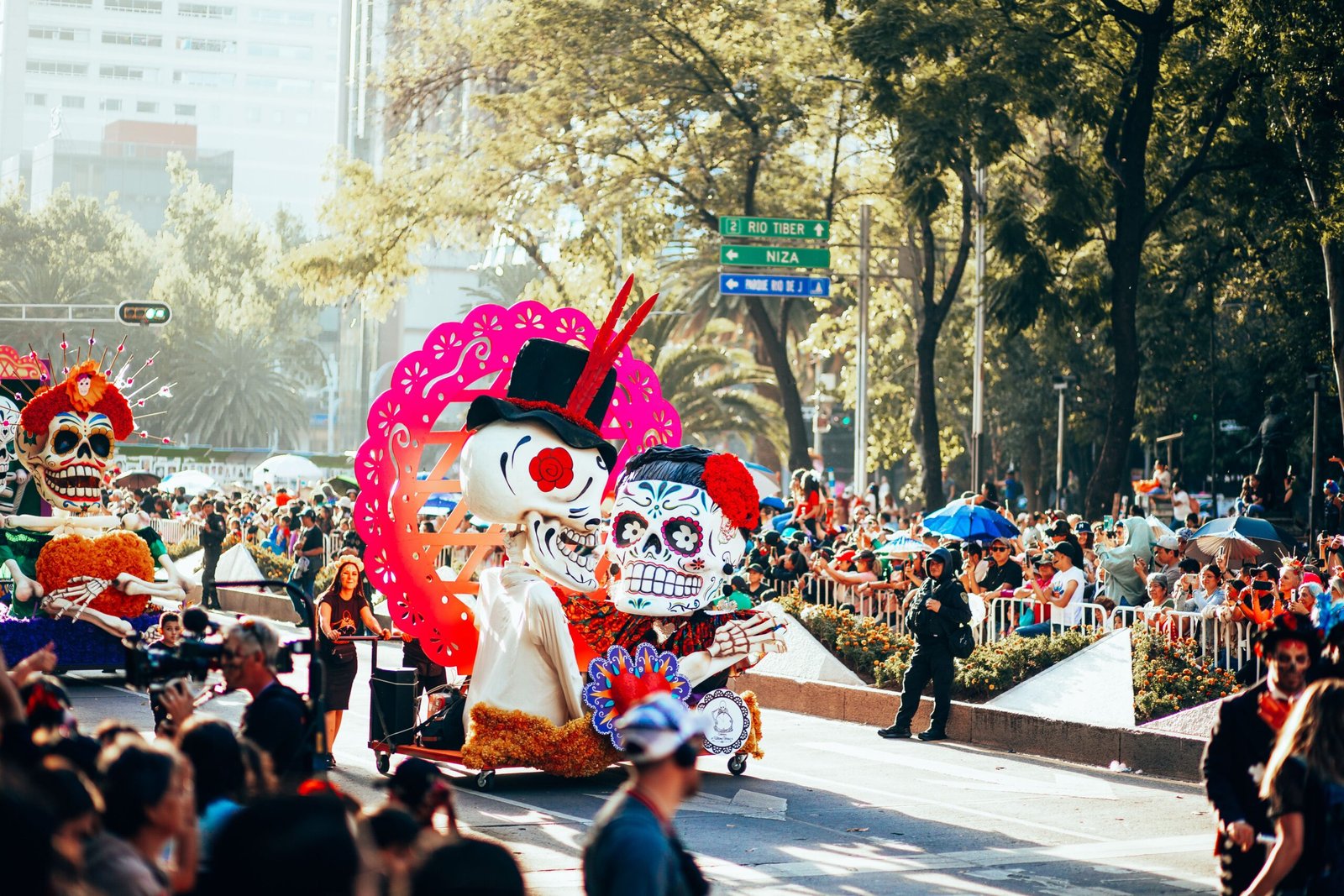 Colorful Day of the Dead parade featuring skeletons and large floats in Mexico City streets.