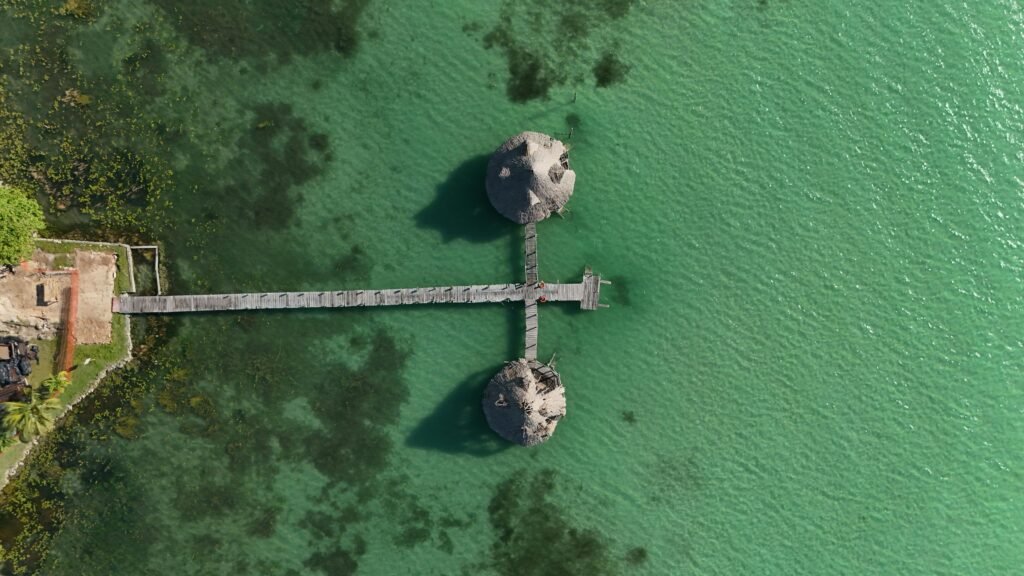 Stunning aerial view over Bacalar Lagoon, Quintana Roo, Mexico, featuring a wooden pier extending into turquoise waters.