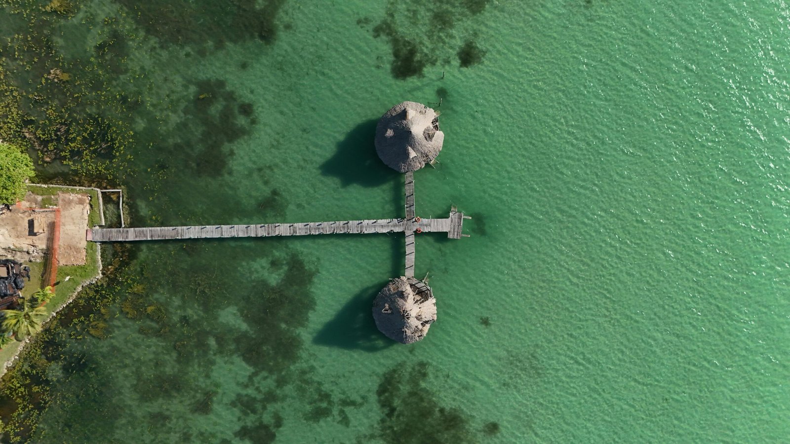 Stunning aerial view over Bacalar Lagoon, Quintana Roo, Mexico, featuring a wooden pier extending into turquoise waters.