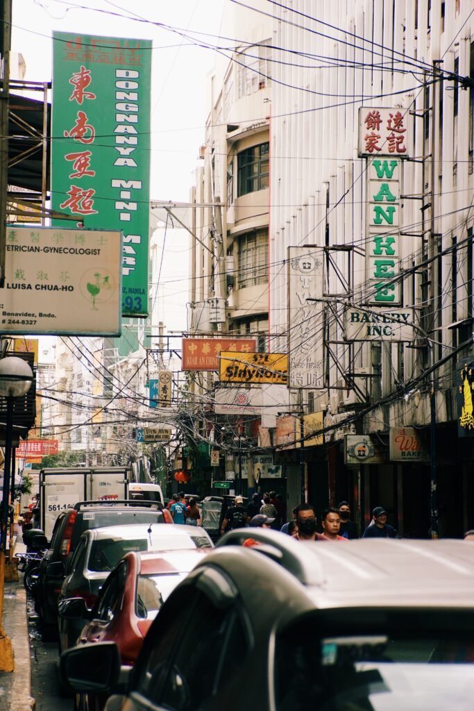 Lively street scene in Manila's Chinatown with busy traffic and vibrant signage.