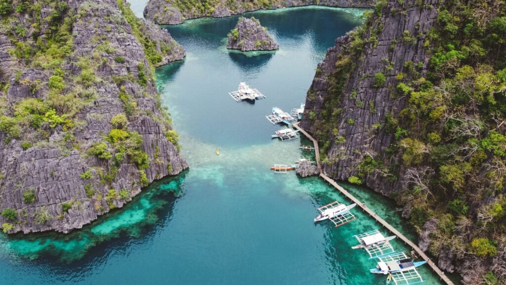 Stunning aerial shot of boats in crystal clear waters surrounded by rocky cliffs in Coron, Philippines.